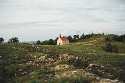 A beautiful view of a cottage on a grass covered field under the cloudy sky