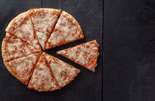 A high angle shot of pizza pieces on a wooden table background with a copy space