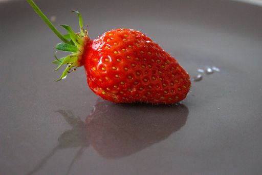 A closeup shot of a strawberry on a dark gray plate