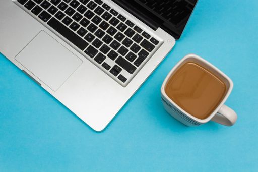 A closeup shot of an opened laptop and a cup of coffee near it