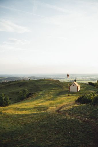 A vertical shot of a small wooden cottage on a beautiful grass covered hill