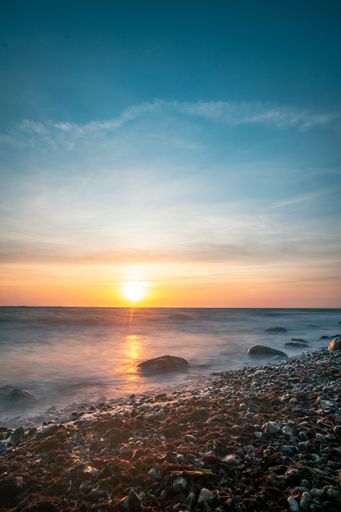 A vertical view of the sunrise at the Baltic Sea with waves in the foreground