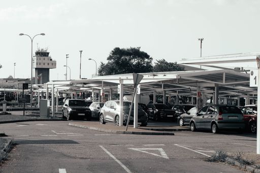 A closeup shot of different vehicles parked in a parking lot with trees on the background