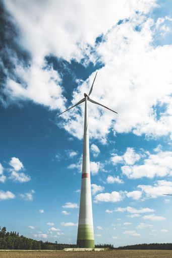 A vertical shot of a tall wind turbine under the beautiful blue sky