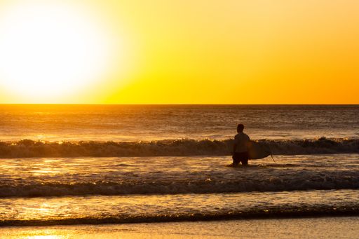 A mesmerizing scenery of male entering the sea at sunset at Jiquilillo beach