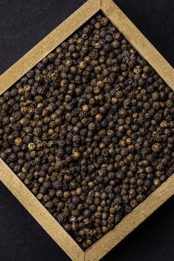 A vertical high angle shot of a box of raw cocoa beans on a black background