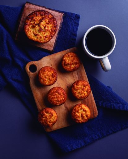 A vertical high angle shot of some homemade cupcakes and a cup of coffee on a blue surface