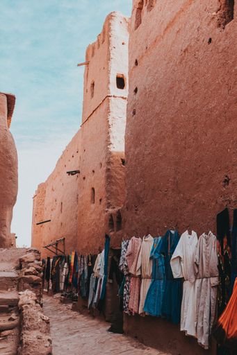 A vertical shot of clothes hanging from a tall fortress wall under a blue sky