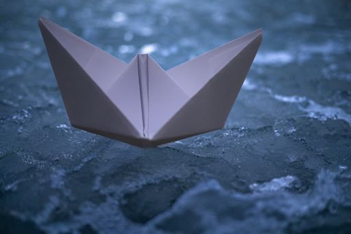 A paper boat on an icy ground