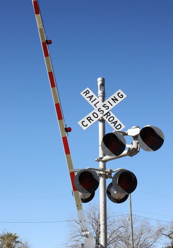 A vertical shot of a railroad crossing sign, lights and protection arm for traffic