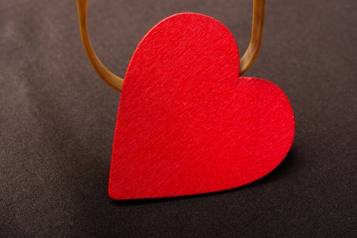 A closeup shot of a wooden red heart on a dark surface