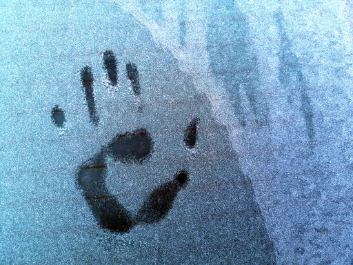 A closeup of the trace of a hand on a car window covered with hoarfrost