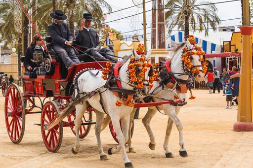 JEREZ, SPAIN - MAY, 09, 2010: Two men dressed in typical flamenco costumes drive a horse-drawn carriage at the Horse Fair in Jerez, Spain.