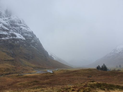 A view of snowy mountains and a field on a rainy day