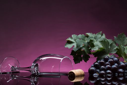 A wine glass and grape on purple surface and background. Winery concept