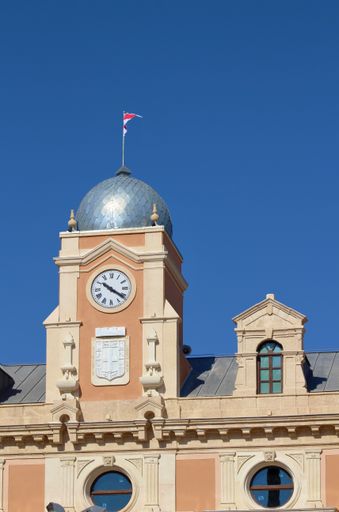 A vertical shot of the facade of the City Hall with a waving flag on top in Almeria, Spain