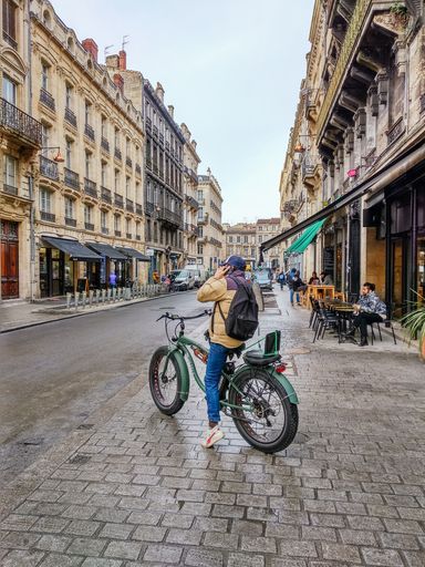 BORDEAUX, FRANCE - DECEMBER, 17, 2018: A young man is talking on his mobile phone on his bike in a central street in Bordeaux, France.