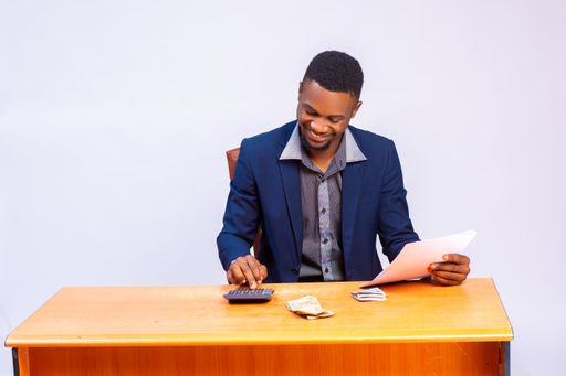 A Nigerian businessman smiled as he analyzes the budget in his hand