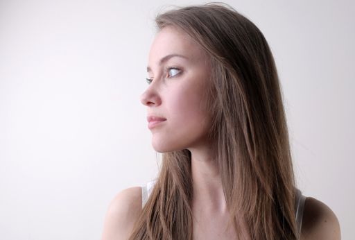 A portrait of an attractive young female standing against a white wall