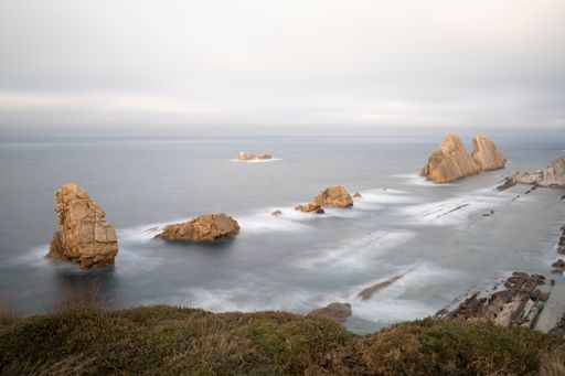 A scenic view of rocky mountain peaks against the seascape under the gloomy sky