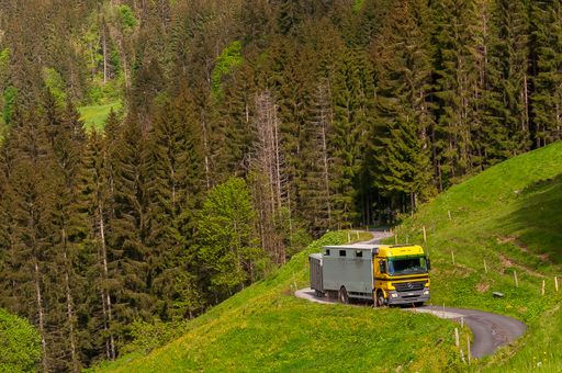 A beautiful shot of the Swiss Alps with a narrow road and yellow vehicle captured in Switzerland