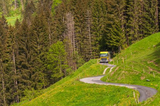 A beautiful shot of the Swiss Alps with a narrow road and yellow vehicle captured in Switzerland