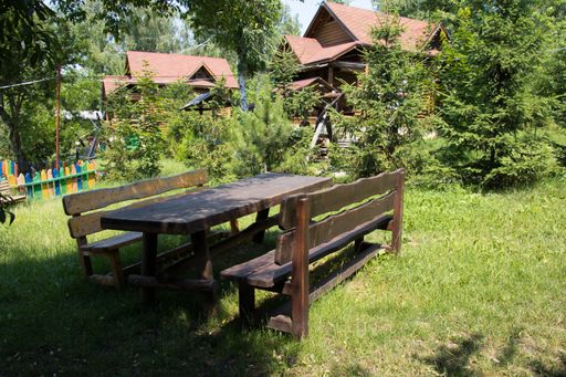 A wide shot of a picnic table in the park in front of cabin with red rooftops