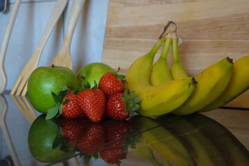 A closeup shot of fresh strawberries, bananas and apples on the table
