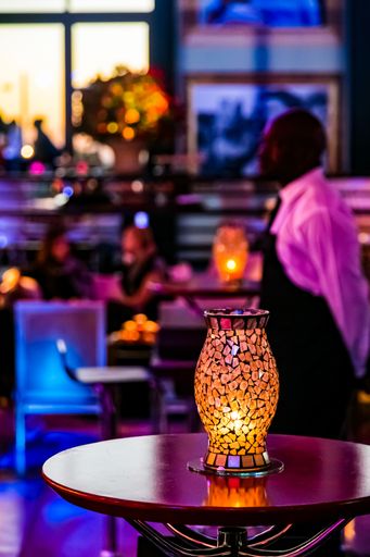 A vertical shot of cocktail party event decor in a dark room with candles and glass lamps.