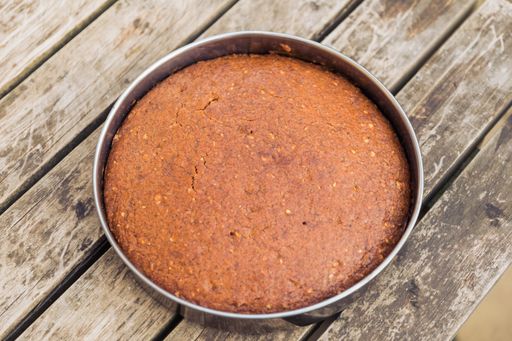A high angle shot of a deliciously baked cake in a round mold on a wooden surface