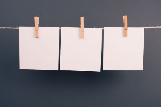 Empty white sheets of paper in a row hanging on a string, copy space for pictures and text, message communication and marketing background