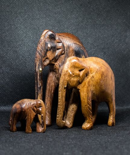 A vertical shot of three elephant sculptures with a grey background