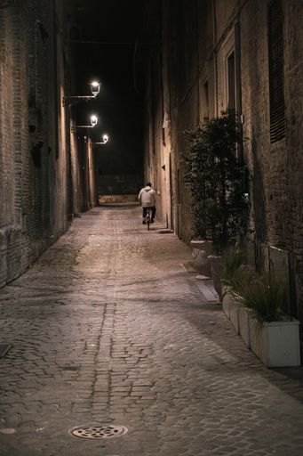A vertical shot of the male on a bicycle in the narrow street in Pesaro, Italy