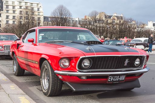 A classic old red car Ford Mustang Mach 1 parked in the street