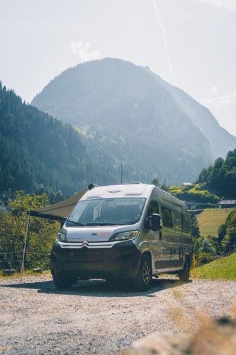 A vertical shot of the McRent camper van in front of the alps in Switzerland