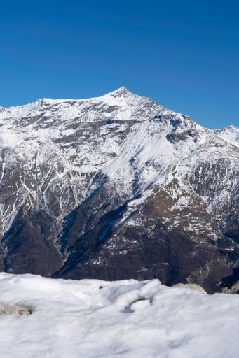 A vertical shot of a snow-covered huge mountain with sharp slopes