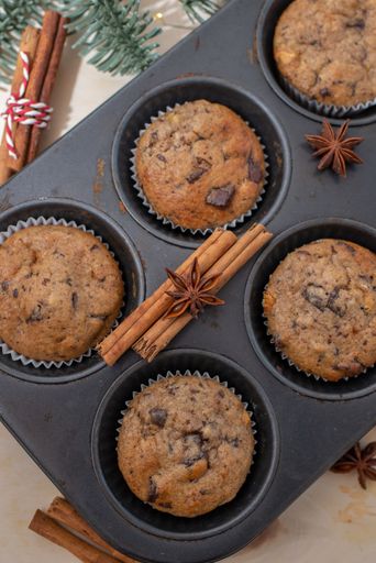 A vertical closeup shot of the homemade chocolate muffins just taken from the oven on the Christmasy background