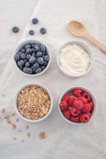 A variety of breakfast food with yogurt, granola and fresh berries in small bowls