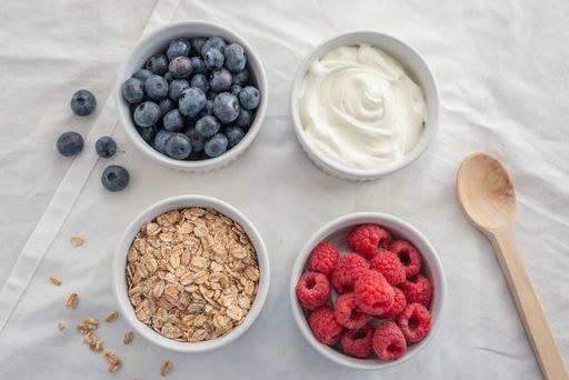 A variety of breakfast food with yogurt, granola and fresh berries in small bowls