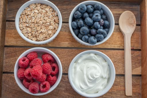 A variety of breakfast food with yogurt, granola and fresh berries in small bowls