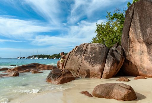 A sexy female wearing a bikini near the rock on a tropical island in Seychelles