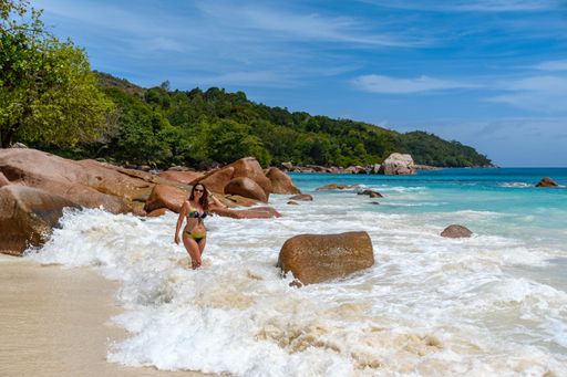 An adult woman wearing a bikini and posing at the Anse Lazio beach in Seychelles