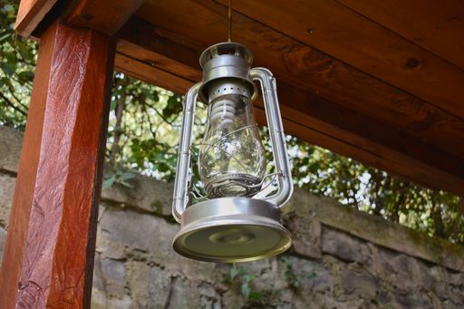 A low angle of a vintage metallic lantern hanging on the wooden ceiling outdoors