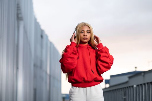 A cheerful African American woman in red sportswear posing for a photoshoot against a grey wall