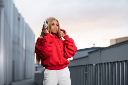 A cheerful African American woman in red sportswear posing for a photoshoot against a grey wall