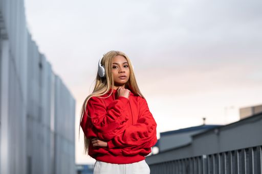 A cheerful African American woman in red sportswear posing for a photoshoot against a grey wall