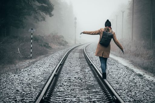 A person walking on the tracks of a train on a foggy day