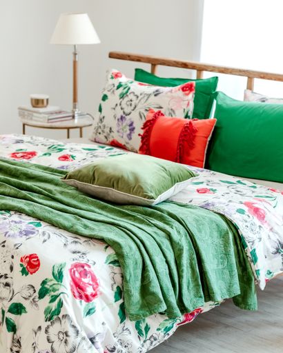 A bed with green and red pillows in a bedroom interior