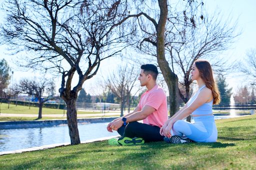 A Caucasian couple doing yoga in a park