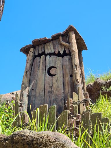 A closeup shot of an old wooden outside toilet in the village against a clear blue sky